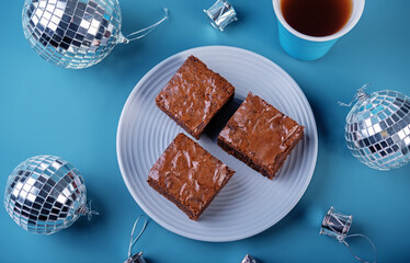Dark chocolate brownie cakes in a plate on a blue background for Christmas holidays