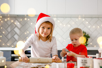 The little girl and boy are preparing dough for gingerbread cookies for Christmas