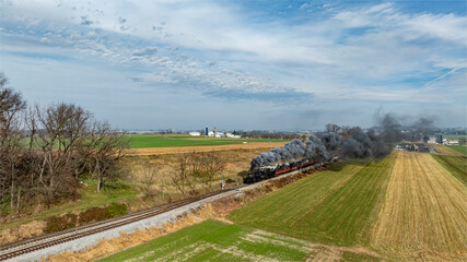 Steam Locomotive Travels Along Countryside Tracks Surrounded by Fields in Rural Landscape