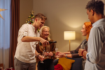 Four friends pouring champagne during a Christmas party