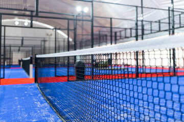 Indoor sports facility showcasing a modern padel court with vibrant flooring and netting, perfect for friendly matches and tournaments