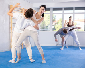 Obraz premium Practiced young female practitioner of self-defense classes demonstrating throw method on her partner