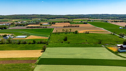 This captivating landscape showcases expansive farmland with a patchwork of green and brown fields