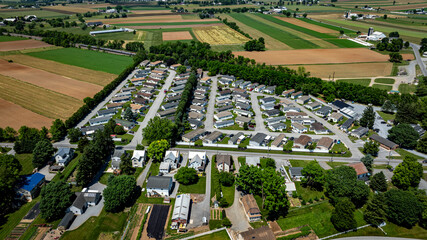 Residential Mobile, Manufactured, Prefab, Home Park with many houses and trees. The houses are white and the trees are green. The sky is cloudy and the houses are spread out