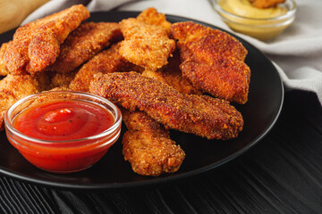 Crispy Chicken Strips with Spicy Sauces on a Rustic Wooden Background