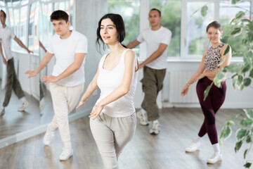 Obraz premium During dance workshop, girl enjoys active dancing, learns new movements, moves synchronously with participants of lesson. Concept of beautiful body through sports, dancing, and active lifestyle
