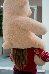 Child Holding a Large Plush Bear with a Smaller Toy in a Indoor Setting