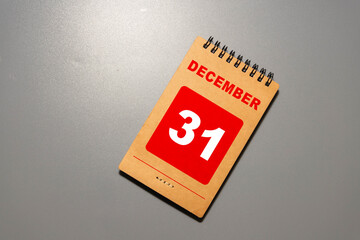 White block calendar present date 31 and month December on wood background.
