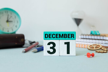 White block calendar present date 31 and month December on wood background.