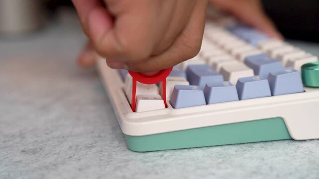 Person using a keycap puller tool on keyboard