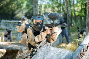 Fototapeta premium Excited paintball player in protective uniform aiming and shooting with guns