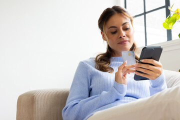 Fototapeta premium At home, woman using smartphone and credit card for online shopping, copy space
