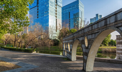 Urban Park Stone Bridge Leading to Reflective City Lake