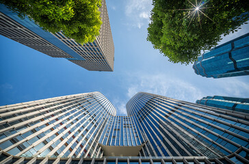 Stunning Low-Angle View of Modern Skyscrapers Surrounded by Lush Greenery