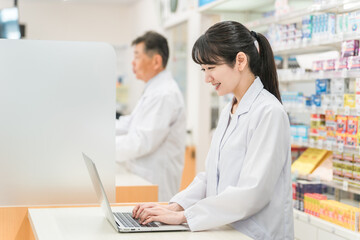 薬局で一緒に働く薬剤師・調剤師（ノートパソコン・タブレットPC）
