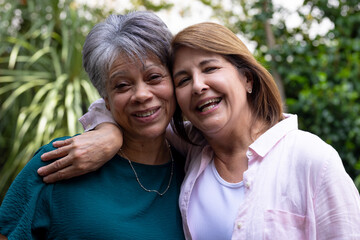Senior female friends embracing outdoors, smiling and enjoying time together