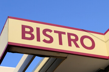 Bistro sign on the exterior of a restaurant building with a blue sky background