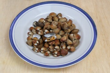 Fresh steamed clams, boiled clams served on a white plate with an easy seafood recipe menu, blood clams