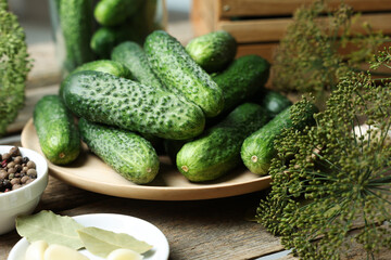 Fresh cucumbers, dill and spices on wooden table, closeup. Preparation for pickling