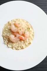 Delicious risotto with shrimps and cheese on black table, top view