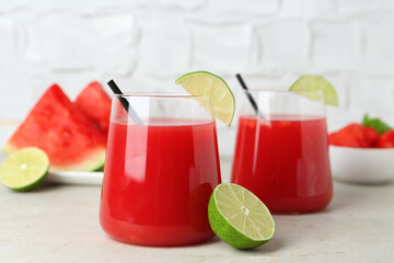 Delicious watermelon drink in glasses and fresh fruits on light table, closeup