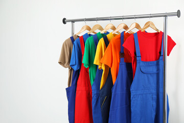 Workers' uniforms on clothing rack near grey wall indoors. Space for text