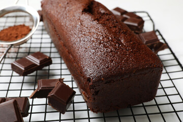 Tasty chocolate sponge cake and ingredients on white table, closeup