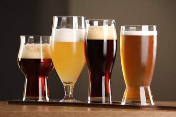 Glasses with different types of beer on wooden table indoors, closeup