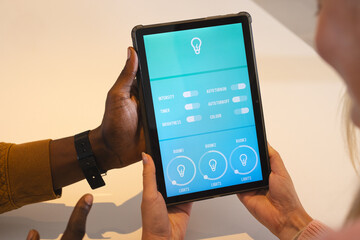 multiracial couple using tablet to control smart home lighting system together