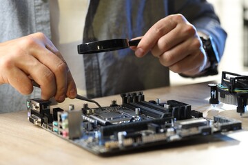 Man installing computer chip onto motherboard at wooden table, closeup