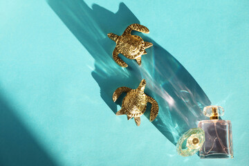 Fototapeta premium Decorative figures of turtles, perfume in bottles and beautiful shadow on light blue background, flat lay. Space for text