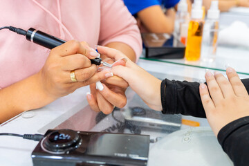 Colombian latina woman in nail spa. Manicurist doing nail cleaning and design. Beauty and fashion. Femininity.