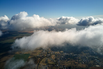 Aerial view from airplane window at high altitude of earth covered with white puffy cumulus clouds