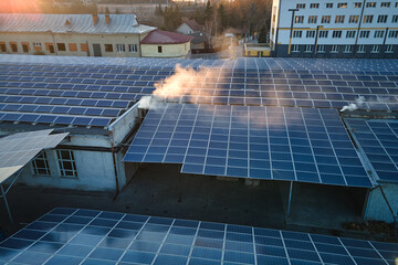 Aerial view of solar power plant with blue photovoltaic panels mounted on industrial building roof...