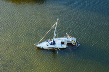 Aerial view of sunken sailboat on shallow bay waters after hurricane in Manasota, Florida