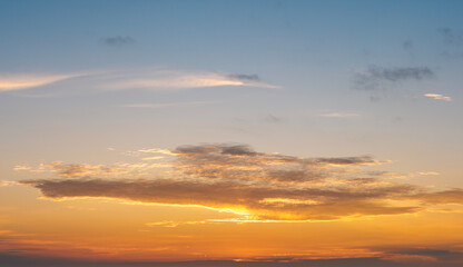 Bright sunset with setting sun behind vivid orange and yellow clouds