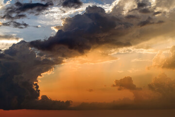 Bright sunset with setting sun behind vivid orange and yellow clouds