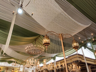 Elegant chandeliers surrounded by luxurious green and white drapes create a majestic ambiance in...