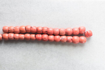 Overhead view of genuine pink coral beads on a marble tray, top view of large stringed pink coral...
