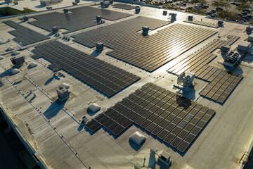 Fototapeta premium Photovoltaic solar panels mounted on industrial building roof for producing green ecological electricity. Production of sustainable energy concept