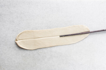 Overhead view of hand pulled noodles being stretched on a table, top view of biang biang noodles being stretched on a marble countertop, process of making biang biang mian