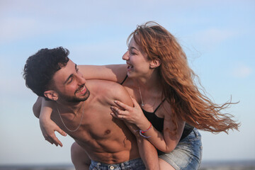 young playful couple having fun on the beach by the ocean on summer day