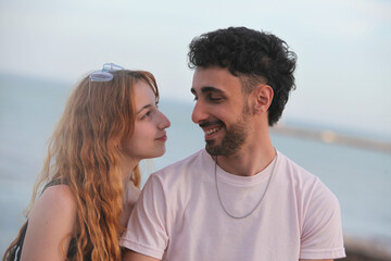 closeup portrait of cute loving young couple on the beach looking at each other at sunset