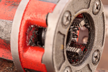 A close-up of a threading die, also known as a pipe die, used for cutting threads on steel pipes, with visible teeth and metallic finish.