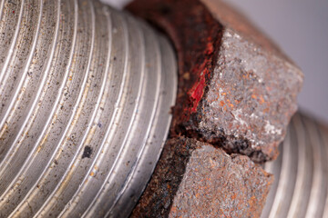 A close-up of a rusty, broken nut attached to a plumbing pipe nipple, showing corrosion and...