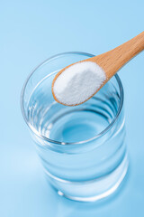 ガラスのコップの水に木のスプーンで重曹を加える瞬間