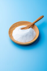 青い背景に重曹の白い粉と木の器と木のスプーン