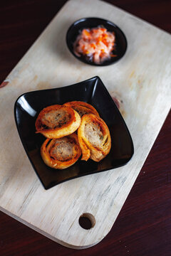 Chicken Egg rolls, made from mixtured minced chicken with tapioca, carrots, scallions and eggs then rolled, steamed and fried. Serving with Salad and Chili