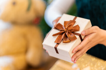 Young Asian woman wearing a red and white Christmas hat surrounded by gift boxes and holding a red...