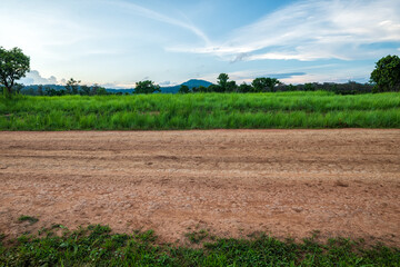 Landscape of gravel road in countryside with meadow. Road in rainy season. Side view of dirt road in forest with sunset. road background.